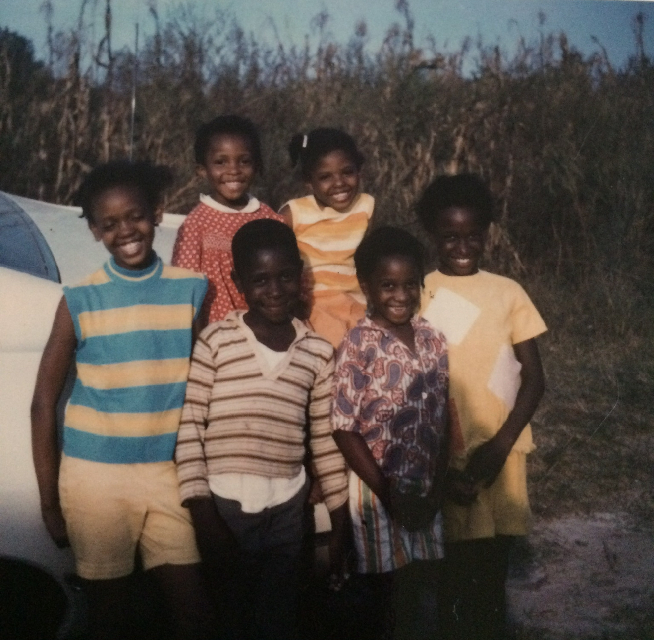 Vintage family photo — six children standing by a car